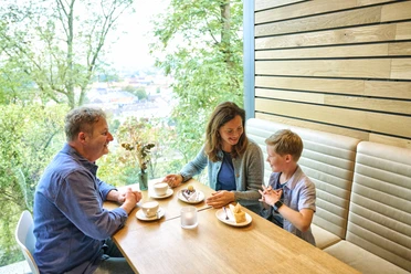 Falada_GRIMMWELT Eine Familie sitzt am Tisch bei Kaffee und Kuchen.