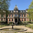 Schloss Etelsen Rotes Backsteinschloss Etelsen mit Springbrunnen im Park unter blauem Himmel.