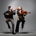 Brueckner_Ladanyi-1.jpg Ein fröhliches Musiker-Duo auf Barhockern: Er spielt Gitarre, sie hält lächelnd eine Geige.