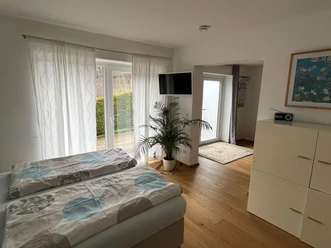 Ferienwohnung Adelenhof Helles Schlafzimmer der Ferienwohnung Adelenhof mit Doppelbett, TV und Terrassentür