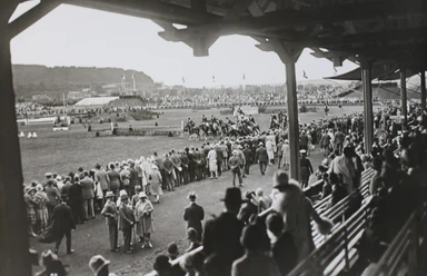 Das Stadion auf dem CHIO-Gelände von der Tribüne aus, auf der sich viele Besucher*innen befinden, in schwarz-weiß.