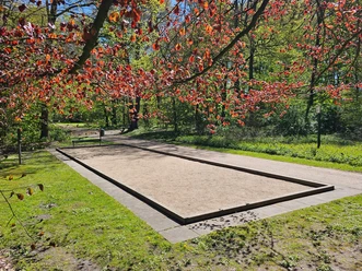 Gesundheitspark Speckenbüttel 20260429_134904 (c) Tanja Mehl_Erlebnis Bremerhaven_WEB.jpg Sandige Boulebahn im Park, umgeben von Wiesen und Bäumen mit rotem Laub.