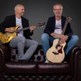 Double Tuff.jpg Zwei Musiker sitzen auf einem Ledersofa. Der eine hält einen Bass, der andere eine Gitarre in der Hand