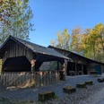 Grillhütte, Vardeilsen, Panoramaweg, CC0 (2).jpg Hölzerne Grillhütte mit Ziegeldach am sonnigen Waldrand, davor ein Schotterplatz mit Bänken.