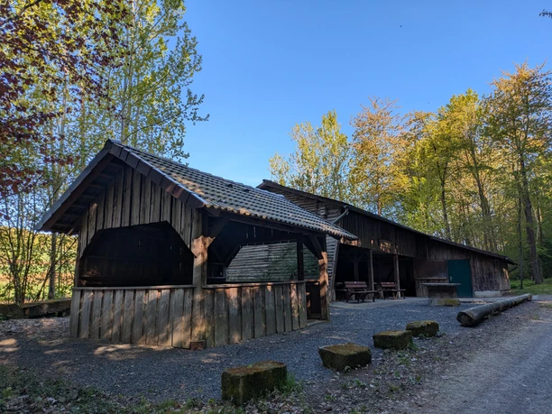 Grillhütte, Vardeilsen, Panoramaweg, CC0 (2).jpg Hölzerne Grillhütte mit Ziegeldach am sonnigen Waldrand, davor ein Schotterplatz mit Bänken.
