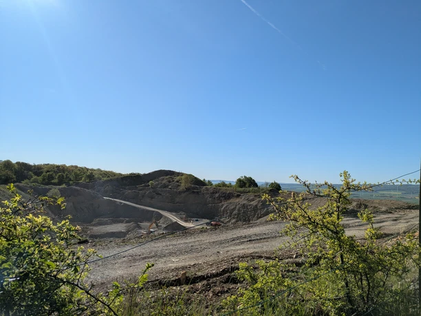 Steinbruch, Vardeilsen, Panoramaweg Felsiger Steinbruch Vardeilsen mit Erdwegen und Bagger unter blauem Himmel.