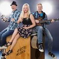 akustik-helden.jpg zwei Herren und eine Dame sitzen mit Instrumenten auf einer großen Box