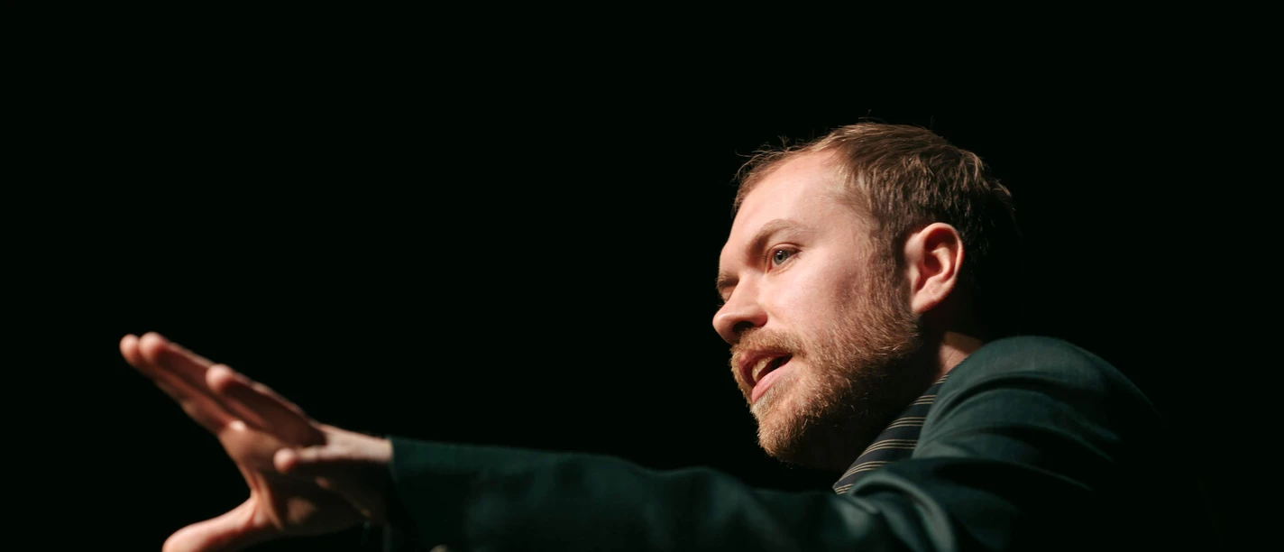 Calle Fuhr An actor on a dark stage with expressive gestures in the spotlight.