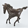 Eine Bronzefigur in Form eines Pferdes vor weißem Hintergrund.