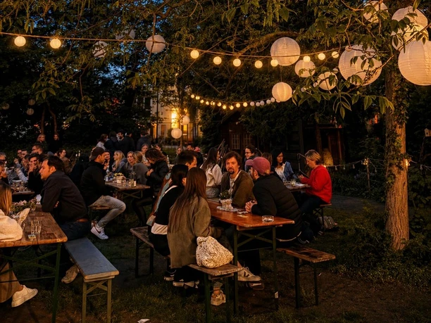 Vineyard in the courtyard of the Carthusian Church Evening get-together on wooden benches under warm fairy lights in a green garden area