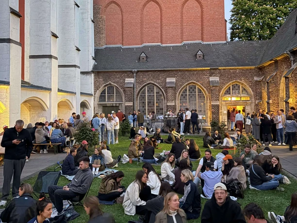 Vineyard in the courtyard of the Carthusian Church Many people sit on the grass in the courtyard of a church in the evening and enjoy being together