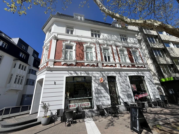 Mam's Burger Straßenansicht von Mam's Burger mit roter Fassade und Außentischen unter Bäumen