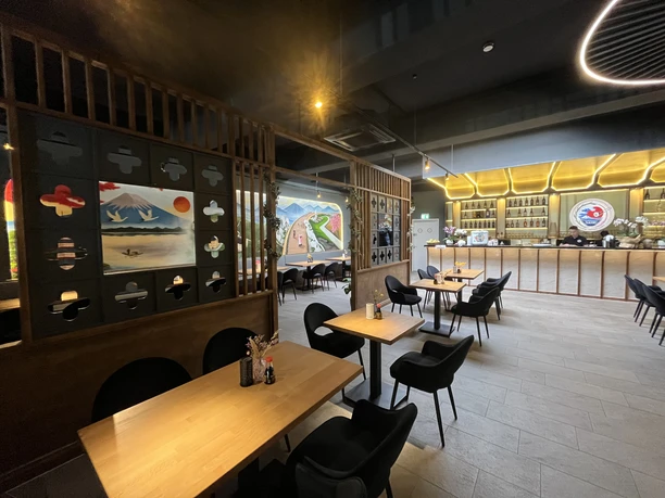 Natsu Modernes japanisches Restaurant mit Holztischen, schwarzen Stühlen und beleuchteter Bar
