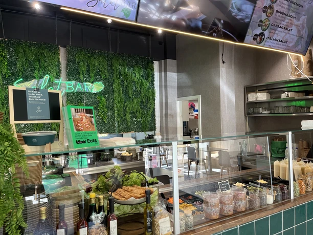 SalatBar Innenraum einer modernen Salatbar mit Theke, frischen Zutaten und grüner Pflanzenwand.