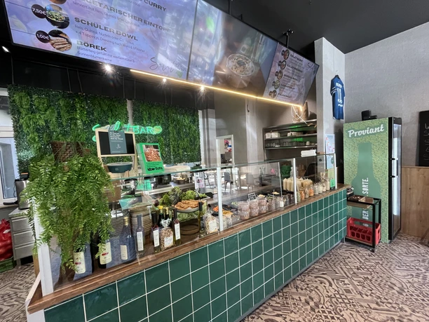 Salatbar Verkaufstheke mit grünen Fliesen, Salatbar, Bowls und digitaler Menütafel im Bistro