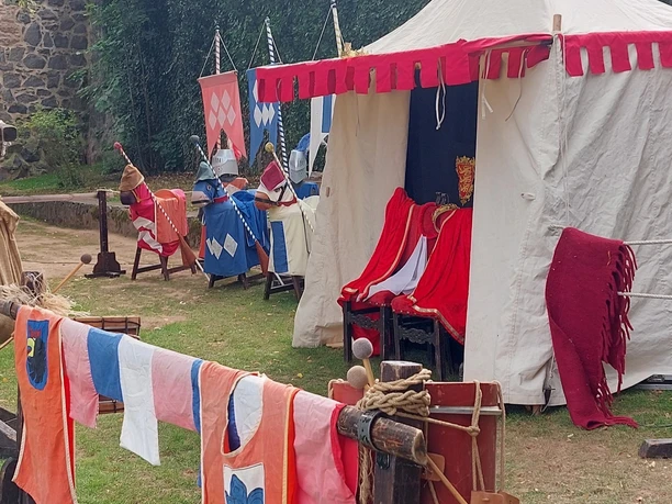 Fritzlar Kaiserfest Auf dem Foto ist ein farbenfrohes Zelt zu sehen. Es handelt sich um das Zelt für das Kinderritterturnier. Im Vordergrund befinden sich bunte Tücher und Fahnen.