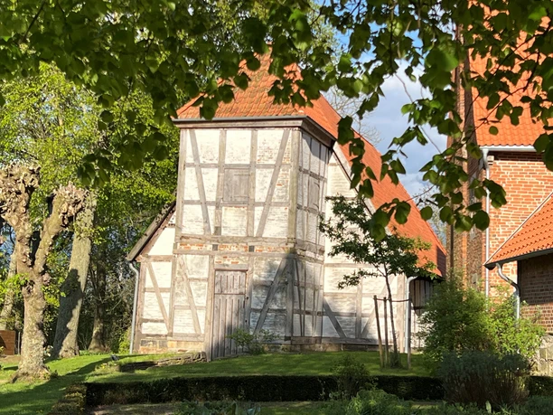 Klosterkirche Fachwerkbau mit rotem Ziegeldach und Backsteingebäude, eingerahmt von grünen Blättern.