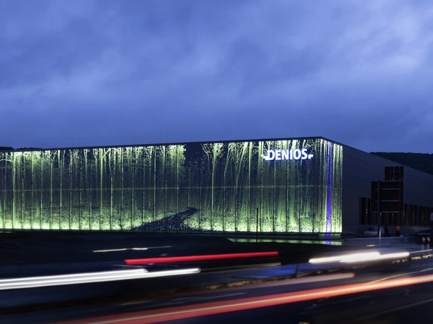 DENIOS Hallen by night. Eine illuminierte Waldkulisse am Fuße des Wiehengebirges.