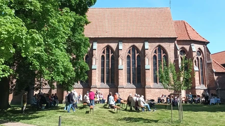 Kirche_Ohlendorf_Himmelfahrt_HD_16zu9.jpg Freiluftgottesdienst: Menschen auf Bänken und ein Posaunenchor vor einer roten Backsteinkirche.
