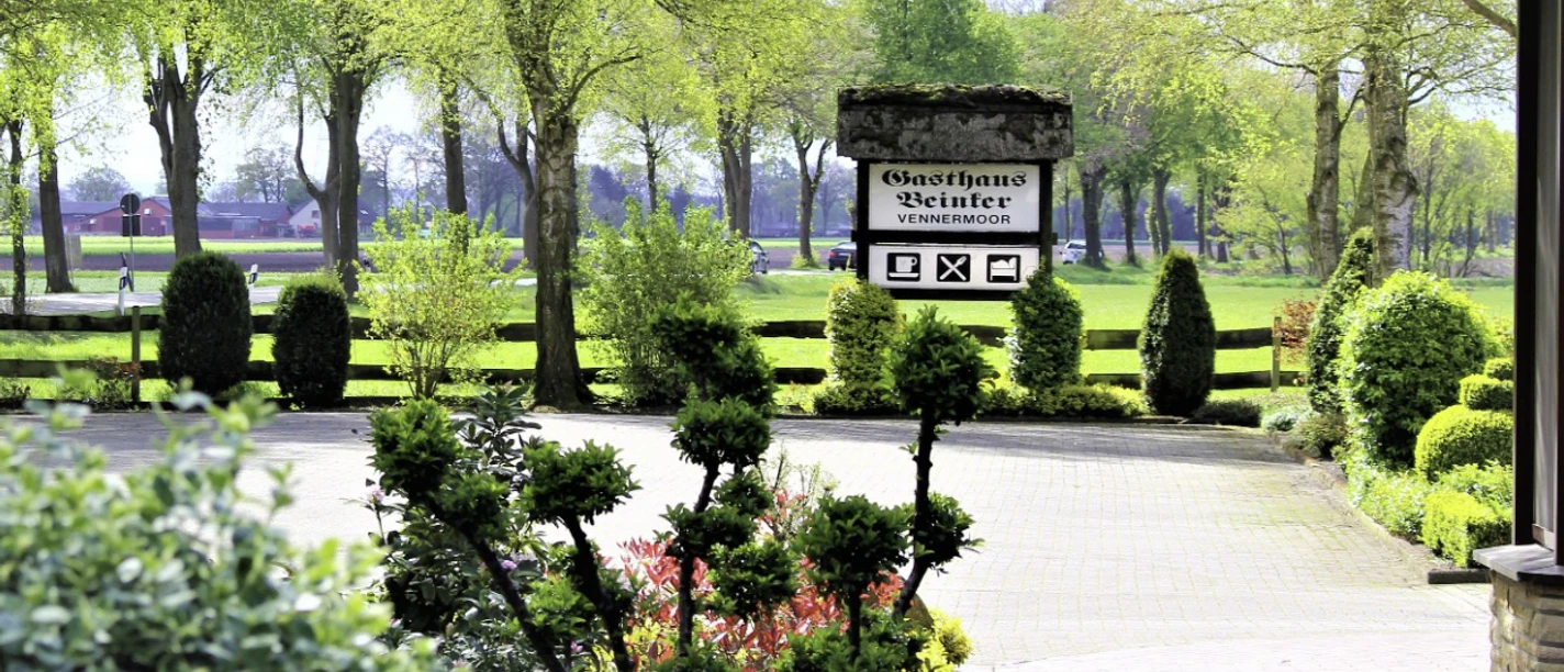 Einfahrt Gasthaus Beinker mit Beeten und Allee