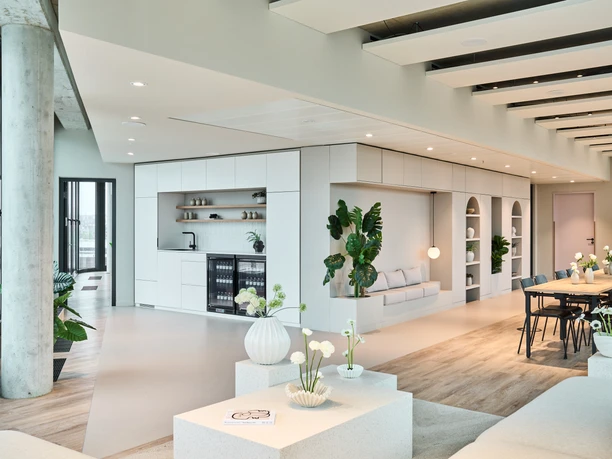 Kreisler - 3 Helle, moderne Büro-Lounge mit Teeküche, Sitznischen und langem Besprechungstisch in minimalistischem Design.