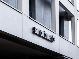 Ein modernes Gebäude mit einem klaren, minimalistischen Design. Das Schild zeigt den Schriftzug "smartments" in stilvoller Schrift.