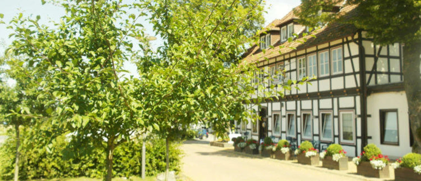 Fachwerkgebäude mit Auffahrt und grüner Wiese mit Baum