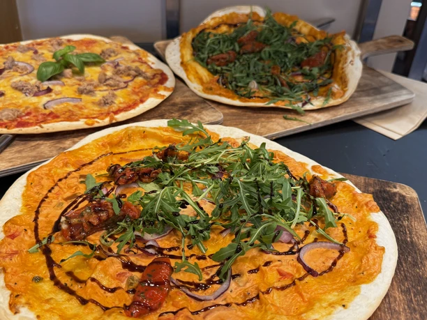 Pizzen auf Holzbrettern liegen auf dem Tisch.