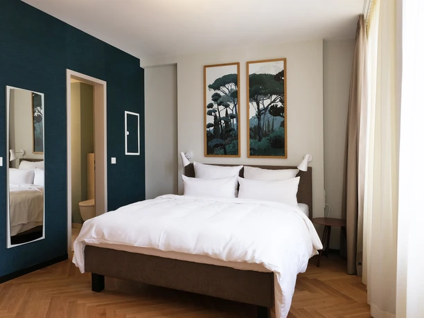 Hood House_HHKS_Space_Bedroom Ein Zimmer im Hood House mit Doppelbett und dekorativen Bildern an der Wand.
