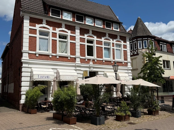 Außenansicht des Lavanta Café mit Backsteinfassade und Terrasse mit Sonnenschirmen.