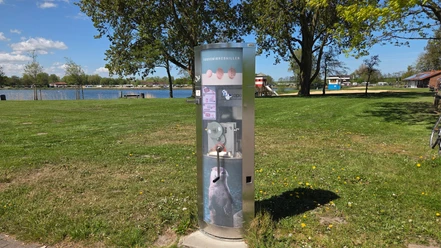 Münzautomat Souvenirmedaillen-Automat mit Otter-Motiv auf sonniger Wiese am Wasser.