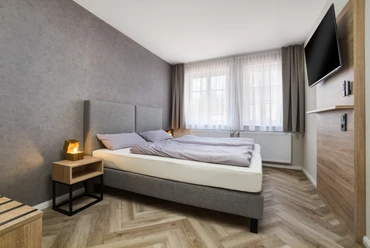 Altstadt Pension Doppelzimmer Zwei Betten an der Wand, daneben ein Nachttisch und ein TV an der Wand