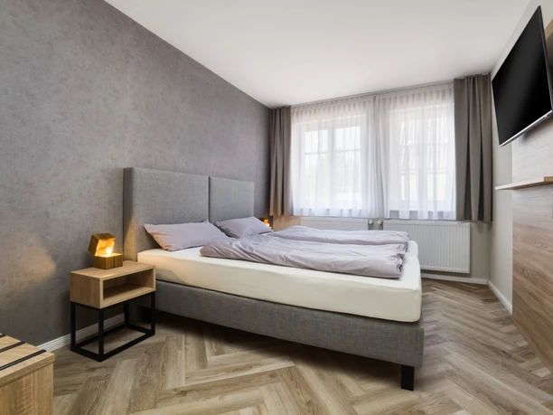 Altstadt Pension Doppelzimmer Zwei Betten an der Wand, daneben ein Nachttisch und ein TV an der Wand