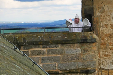 festung-anruechig.jpg Ein Mann in langem Nachthemd und mit Zipfelmütze mit Nachttopf an einem Wachturm der Festung Königstein