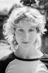 Ann Esswein Portrait of a young person with curly hair and a calm look in black and white.