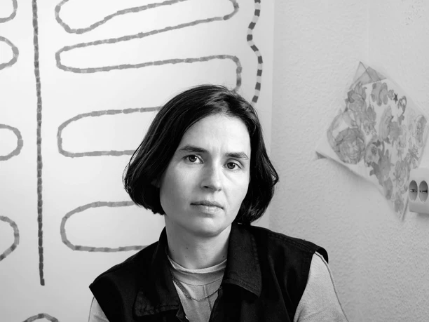 Clara Umbach Portrait of a seated person in front of an abstract drawing in an interior.