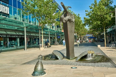 Stadtansichten von Bremerhaven Bronzebrunnen Bugwelle in Form eines Schiffsbugs mit Galionsfigur in einer Fußgängerzone.