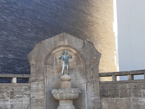20220411_144636 (c) Yelena Iskhakova_Erlebnis Bremerhaven_WEB.jpg Steinerner Ludwig-Krüder-Brunnen mit kleiner Bronzefigur auf einer Kugel und zwei Steinbänken.