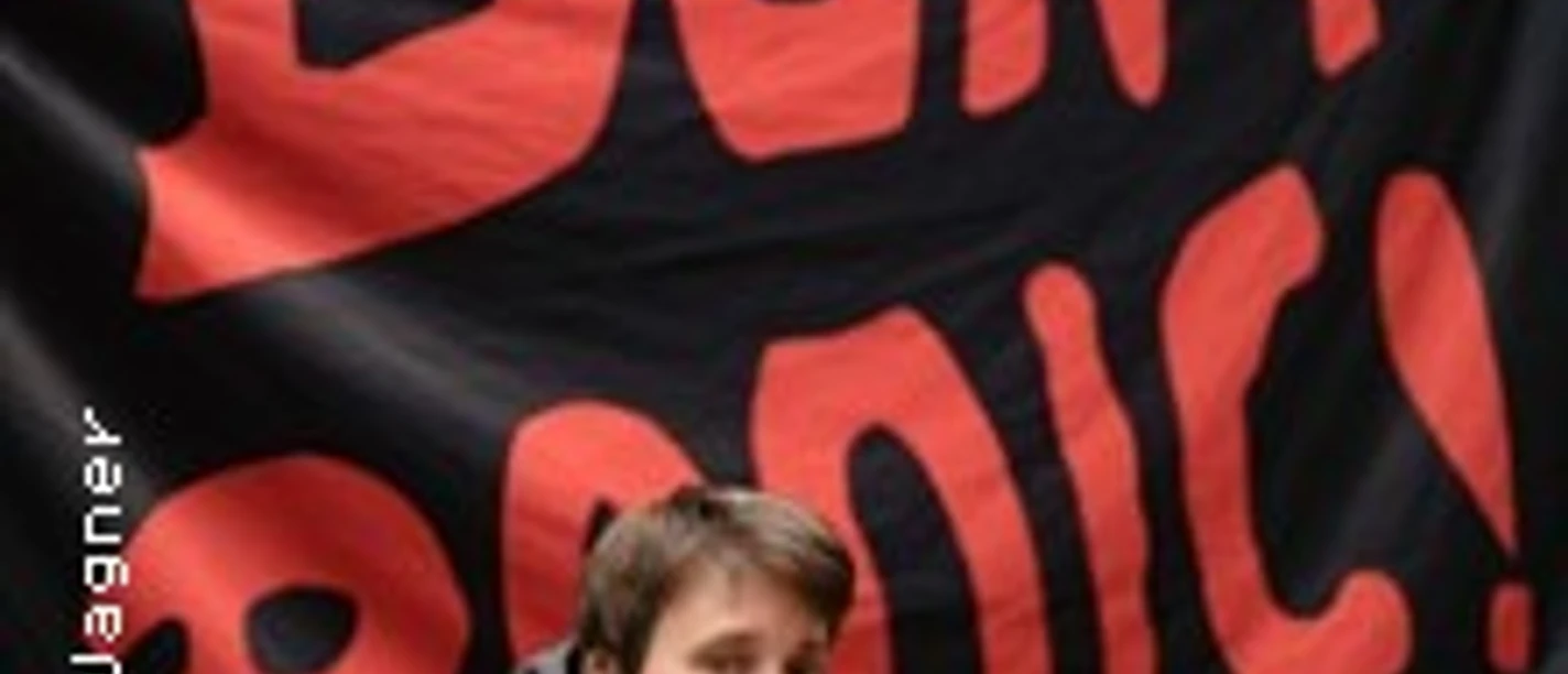 Person lehnt vor schwarzem Banner mit großem roten Schriftzug Don’t Panic!