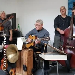 Mehrere Musiker spielen Akustikgitarre und Kontrabass in einem kleinen Innenraum.