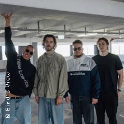 Vier Bandmitglieder von Bird's View stehen in einer Parkgarage, einer winkt in die Kamera