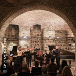 Kammerensemble mit Streichern und Bläsern in historischem Gewölbekeller vor Publikum.