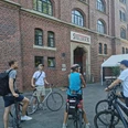 RollOut: On post-colonial traces Cyclists stand in front of a red brick building with the entrance to the Stollwerck community center