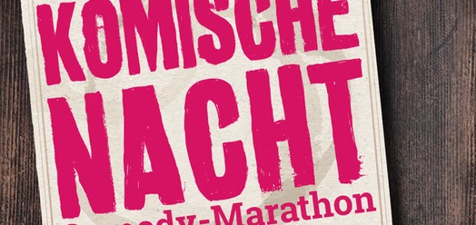 Plakat zur Komischen Nacht mit pinker Schrift auf hellem Papier vor dunklem Holz