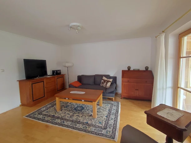 Wohnzimmer mit Schlafcouch & Tür zum Wintergarten