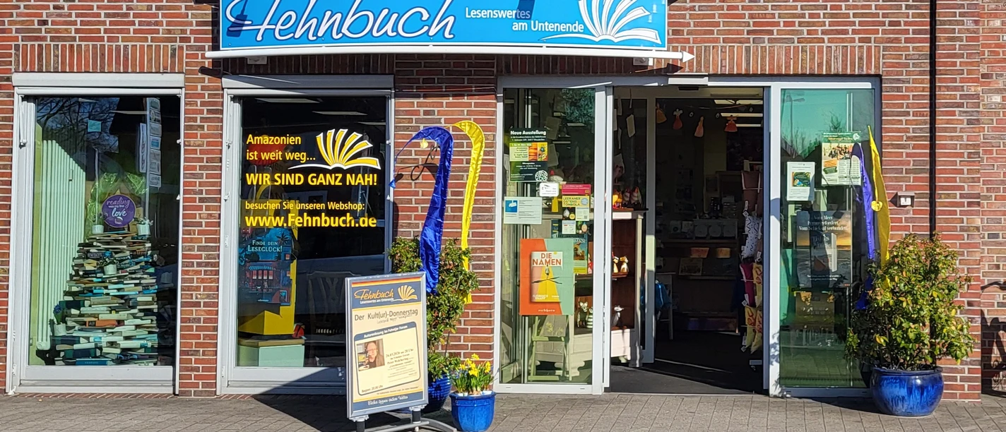 Fehnbuch - Eingang - neues Foto von 2026.jpg Eingang der Buchhandlung Fehnbuch in einem Backsteingebäude mit großen Schaufenstern.