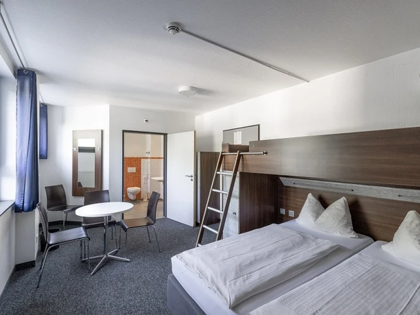 Barrierearmes Zimmer Bright, barrier-free room with double bed, bunk bed, seating area and open bathroom access