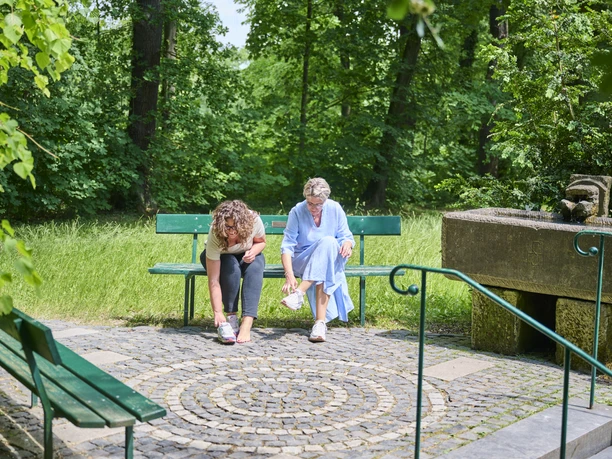 Kneipen im UNESCO Welterbe Bergpark Wilhelmshöhe_MULANG_Armbeclen Auf einer Bank sitzen zwei Frauen neben dem Arm,kneippbecken am Mulang.