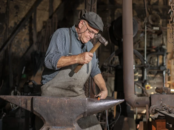 Museumsschmied Markus Schmülling Schmied bearbeitet glühendes Metall auf Amboss in traditioneller Werkstatt.