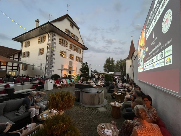 Schloss Whyer Open Air Kino im Innenhof des Wasserschlosses Wyher mit Leinwand, Sitzgelegenheiten und Besucherinnen und Besuchern in stimmungsvoller Abendatmosphäre